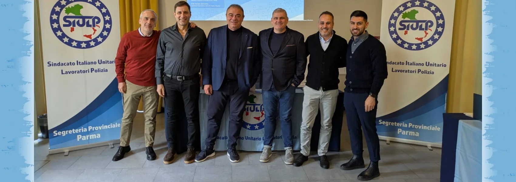Sei rappresentanti del SIULP in piedi davanti ai roll-up del sindacato durante il convegno con Felice Romano, 2025.